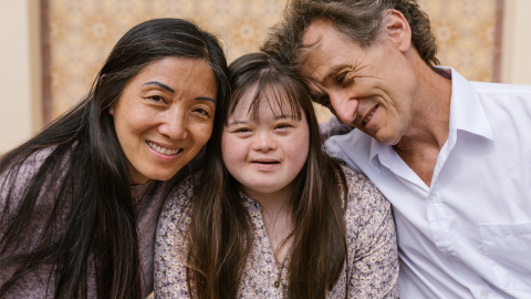 Mother, adult daughter, and father smiling