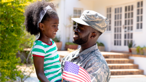 Military family in front of their home with American flag