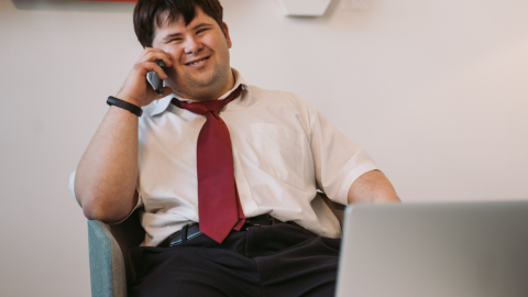 Adult with disabilities smiling in front of their laptop